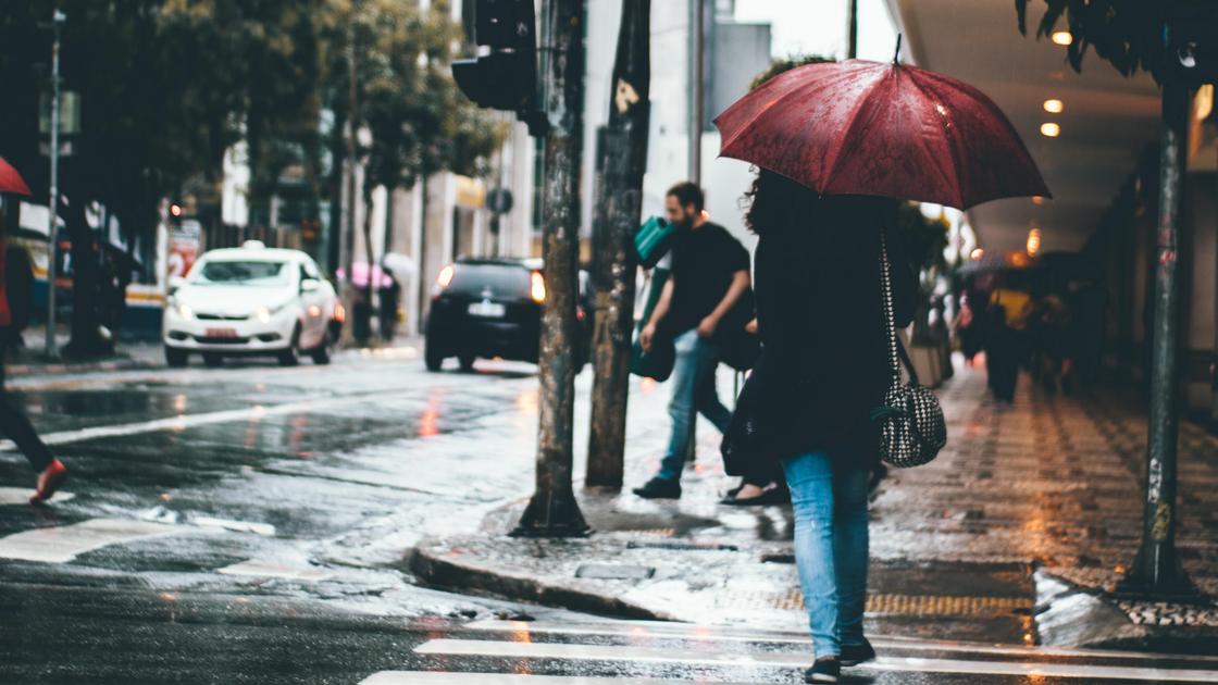 Девушка с зонтом по улице идет под дождем