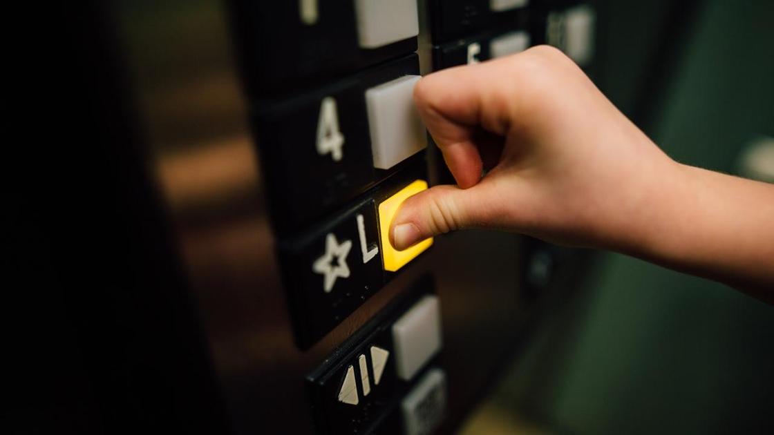 Человек нажимает пальцем на кнопку в лифте