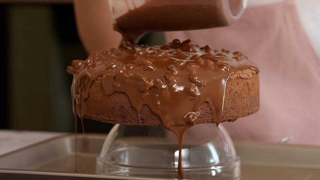 Шоколадный торт с вишней покрывают шоколадной глазурью с орехами
