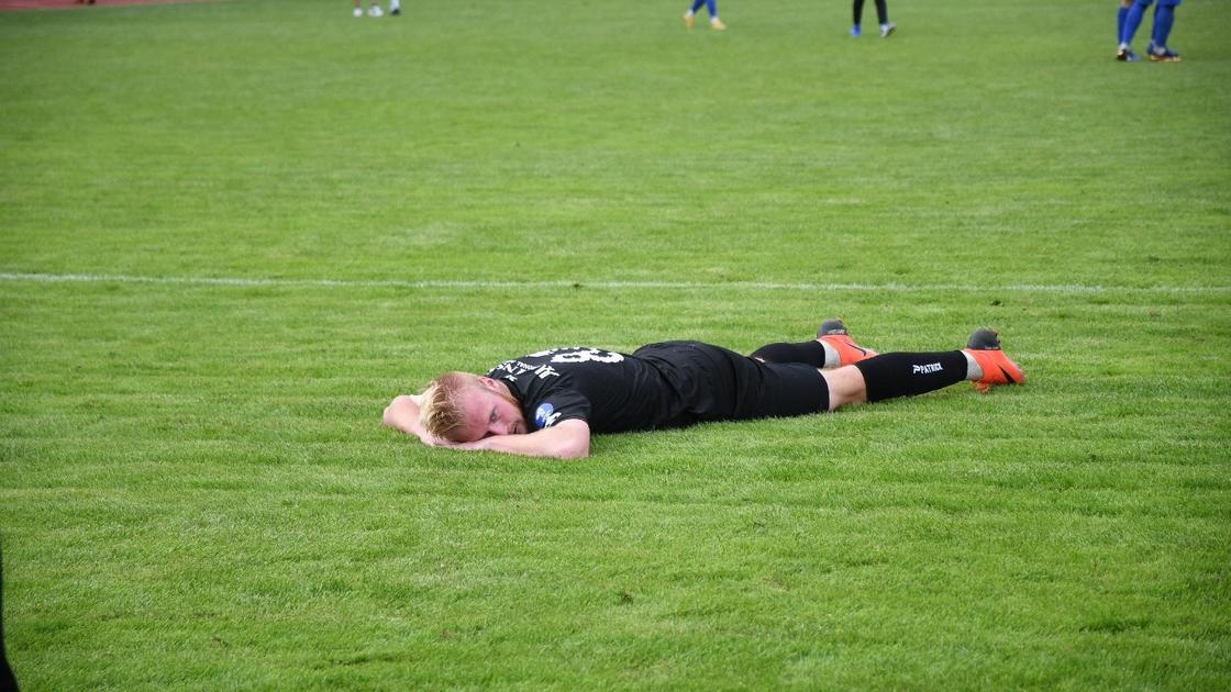 Футболист лежит на газоне