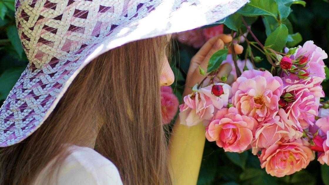 Девушка в шляпе нюхает цветы
