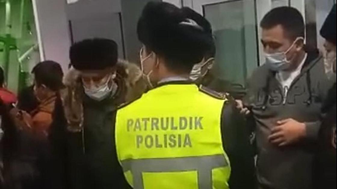 Полицейский стоит рядом с пассажирами в аэропорту