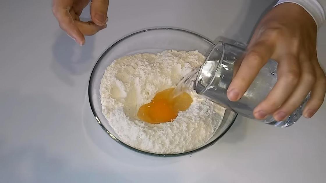 В миску с мукой и яйцом вливают воду