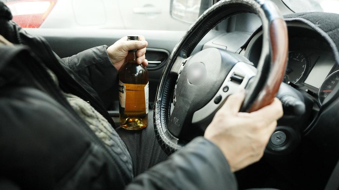 Водитель держит виски за рулем