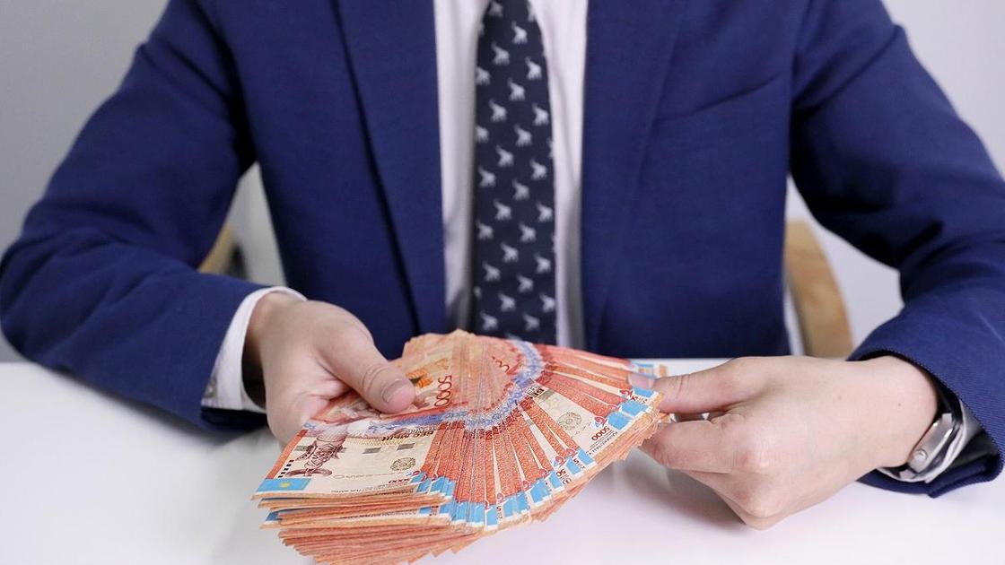 Мужчина в костюме держит в руках пачку денег