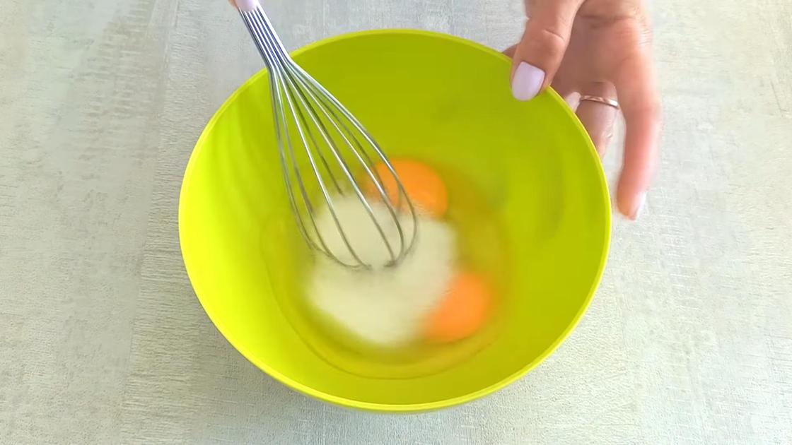 Смешивание яиц с сахаром венчиком в пластиковой миске