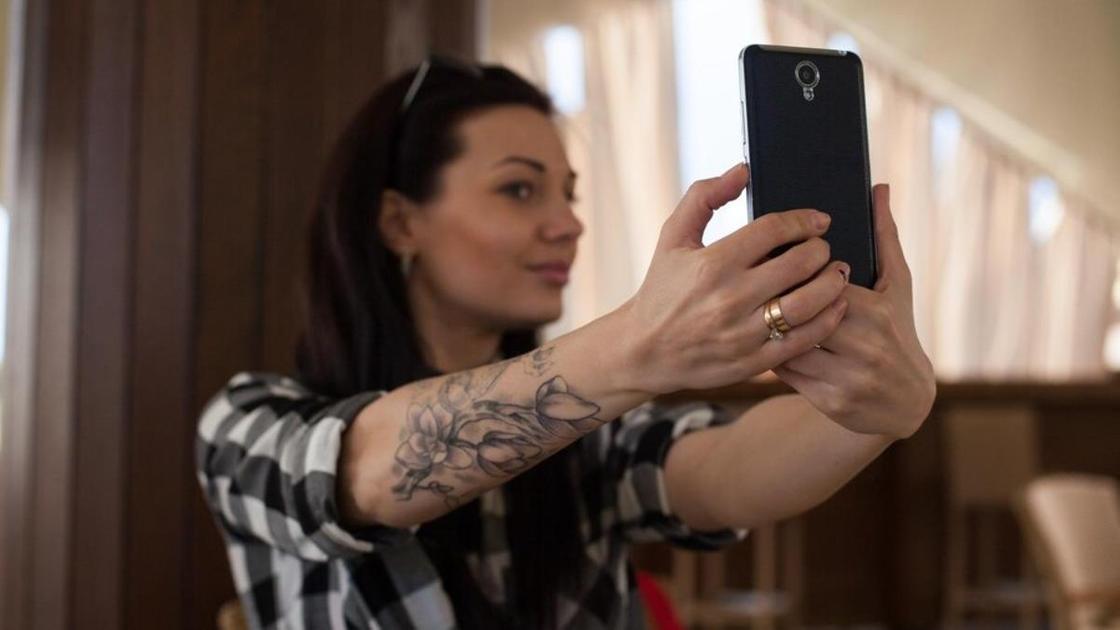 Dívka s tetováním na paži si dělá selfie