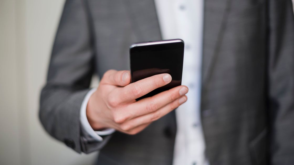 Мужчина в костюме держит смартфон