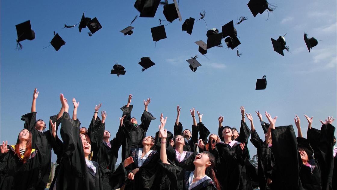 Студенты подбрасывают в воздух квадратные академические шапочки