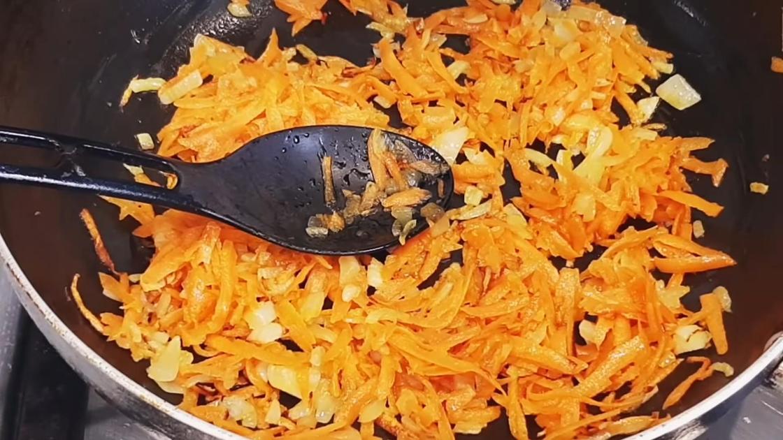 Нарезанная лук и тертая морковь жарятся на сковороде