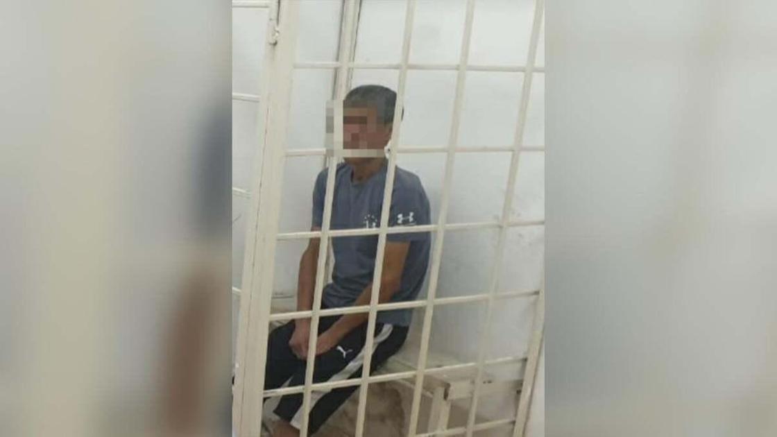 задержанный мужчина сидит в камере