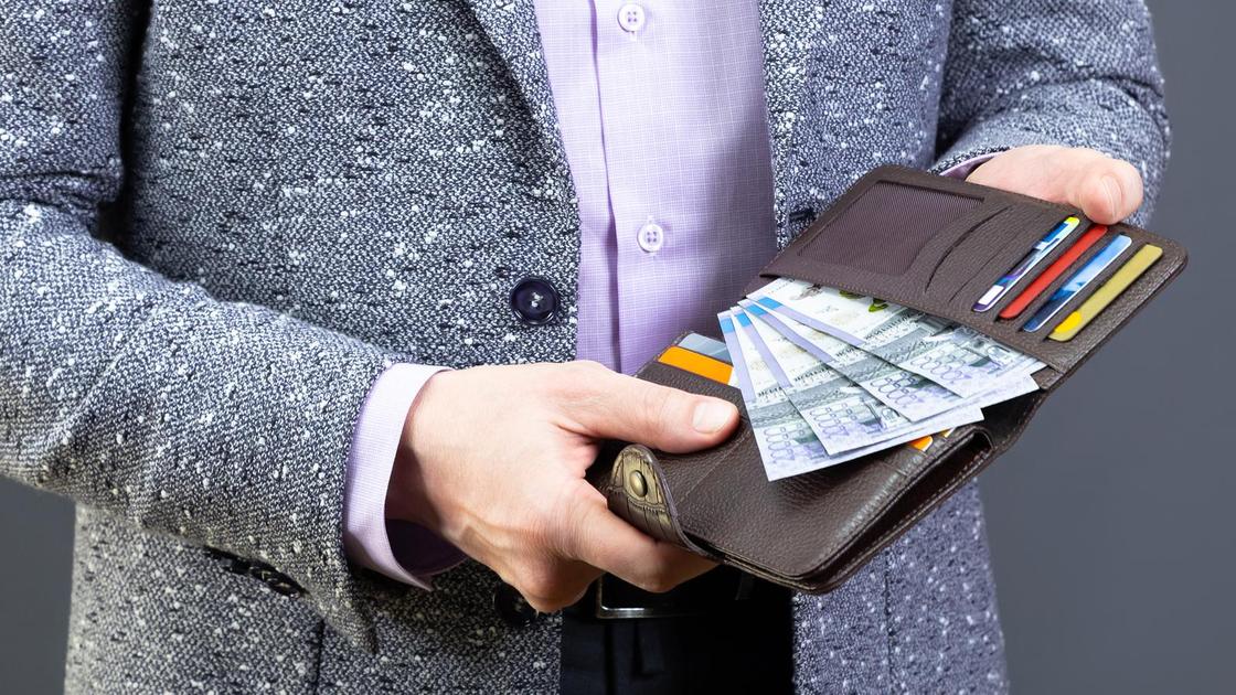 Мужчина держит в руках кошелек с деньгами