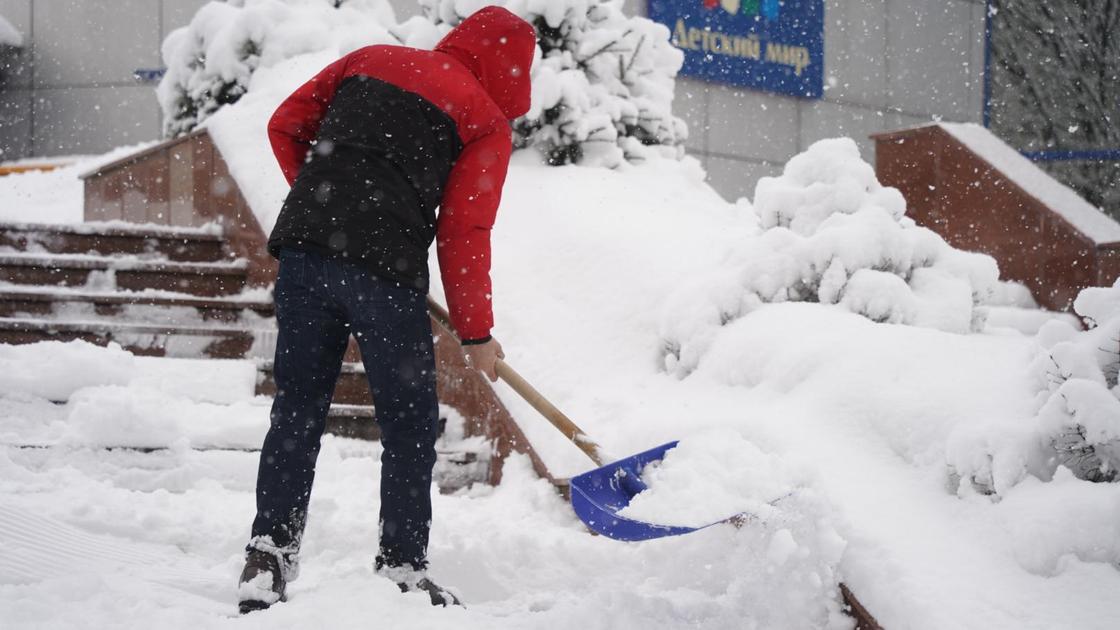 Сыртта қар тазалап жүрген адам