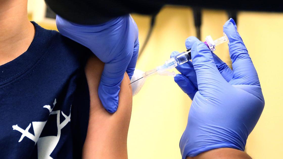 Врач в синих перчатках ставит вакцину ребенку