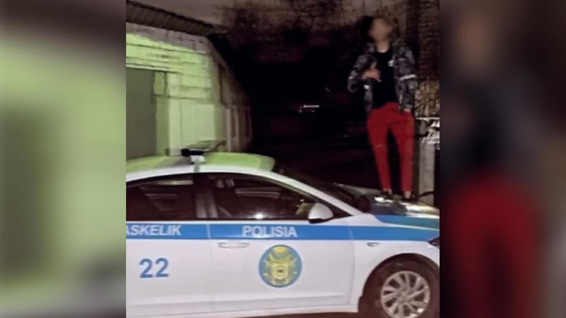 Молодой человек стоит на служебной машине полицейского