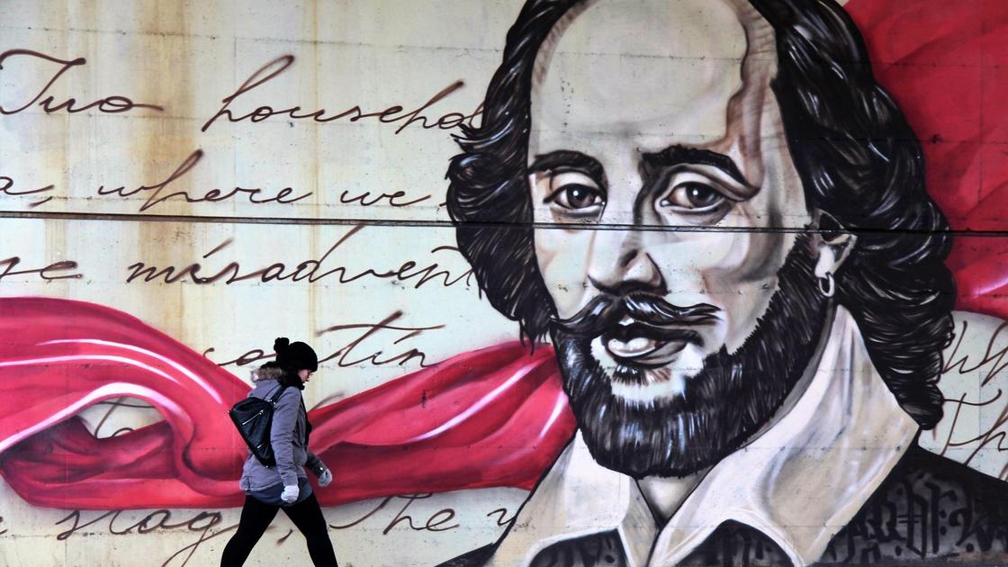 Девушка идет рядом с граффити с изображением Шекспира