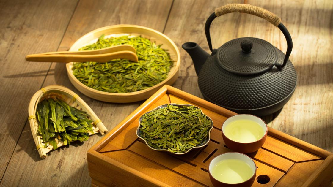 Чайник, листья зеленого чая, чашки