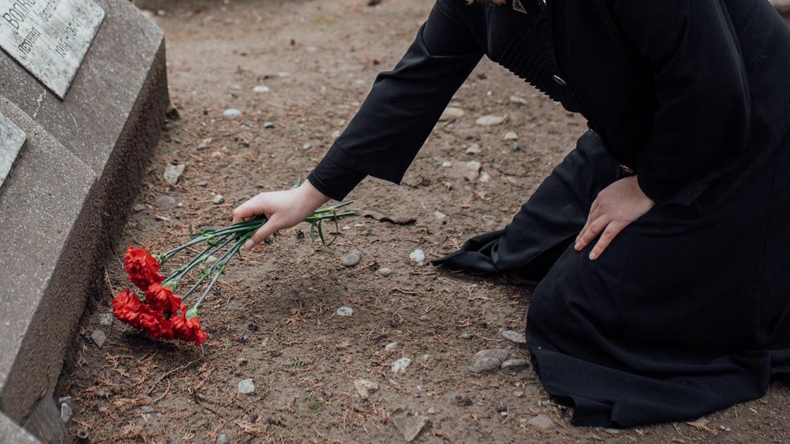 Девушка возлагает цветы к могиле