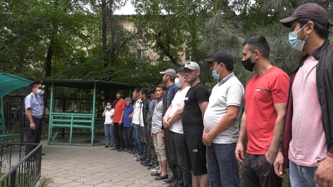 Мужчины стоят в ряд перед двумя стражами порядка