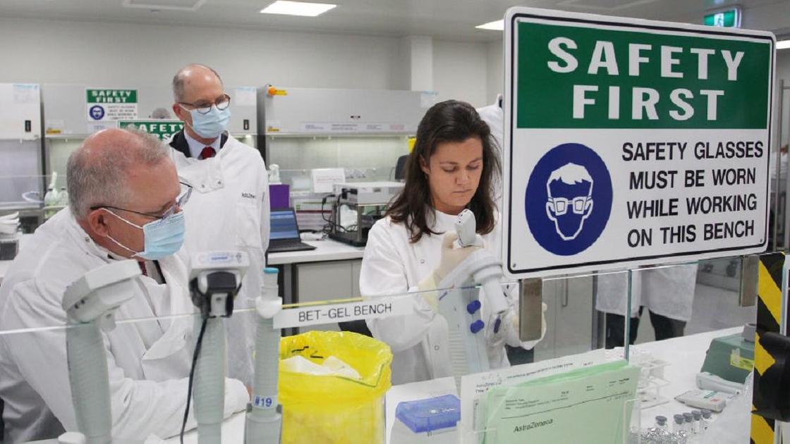 Ученые в лаборатории в белых халатах и масках