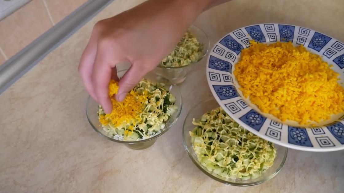 Тертым желтком посыпают разложенный в креманки салат