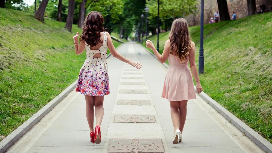 Две девушки идут по тротуару