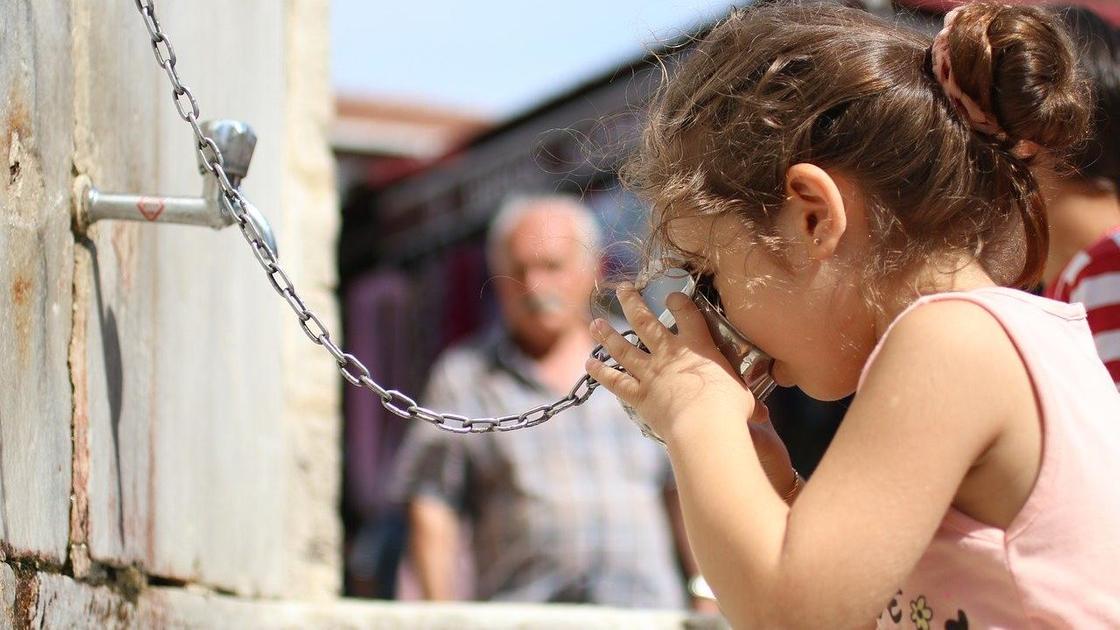 Девочка пьет воду из металлической кружки