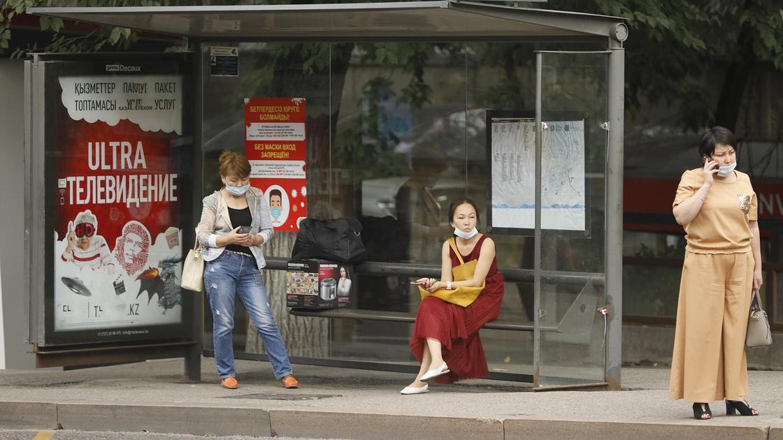 Женщины ждут автобус на остановке