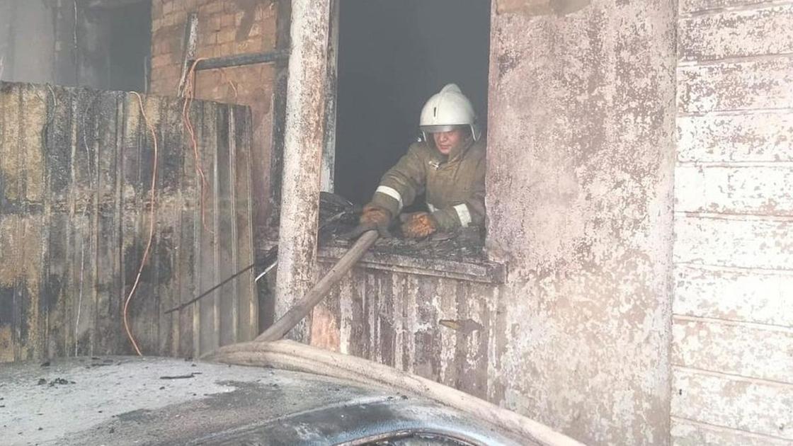 Пожарный стоит за окном в пострадавшем от пожара здании