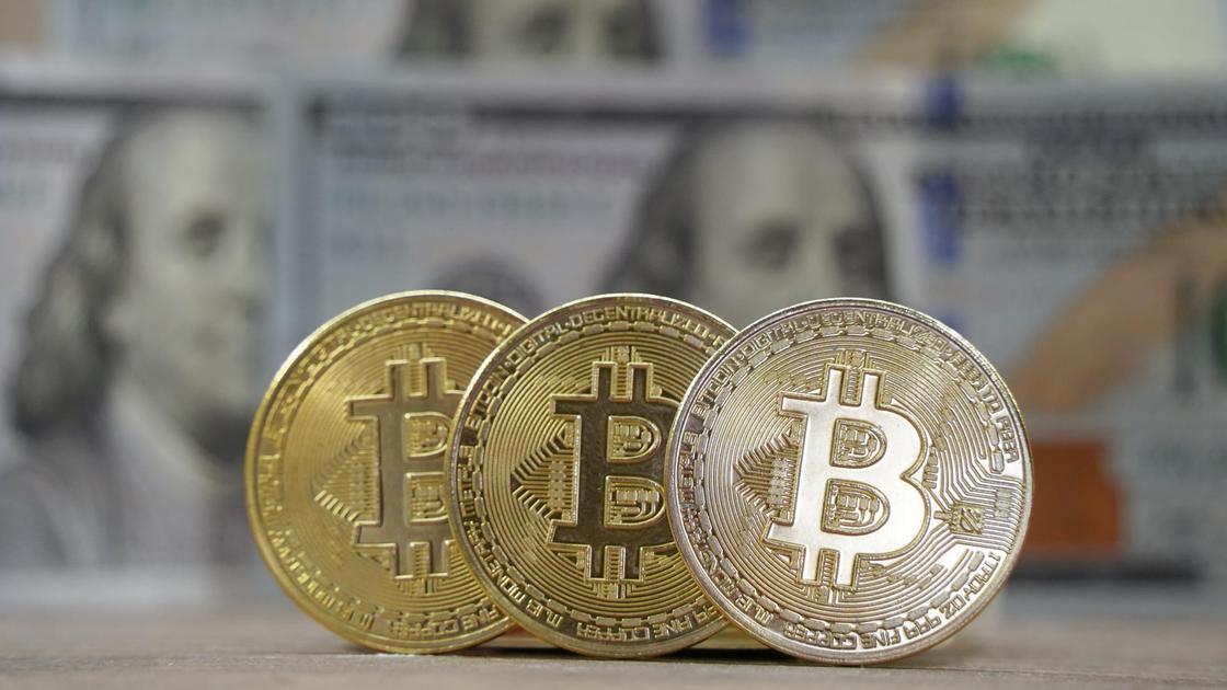 Монеты биткоинов стоят ребром на фоне долларов