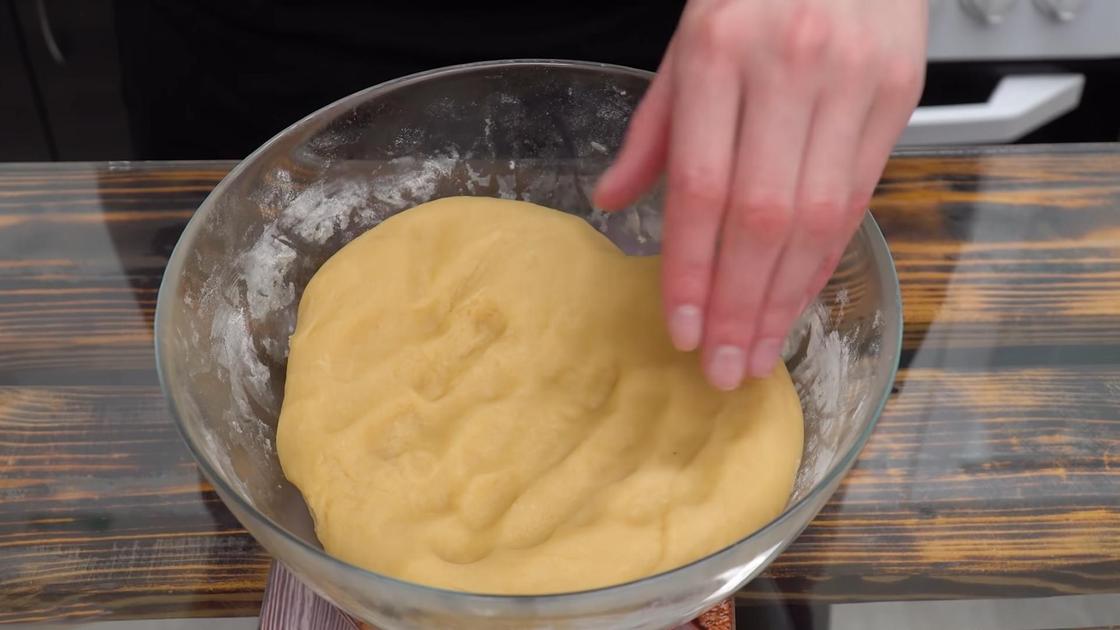 Рукой обминают вымешанное тесто для коржей на «Медовик»