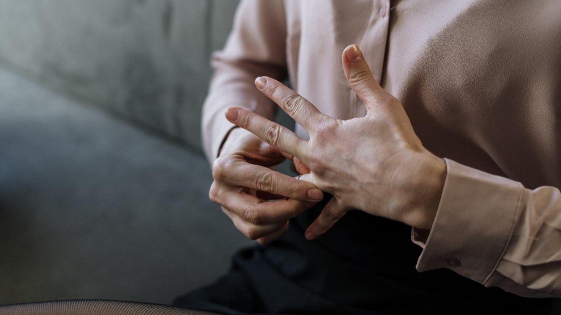 Женщина снимает обручальное кольцо с пальца