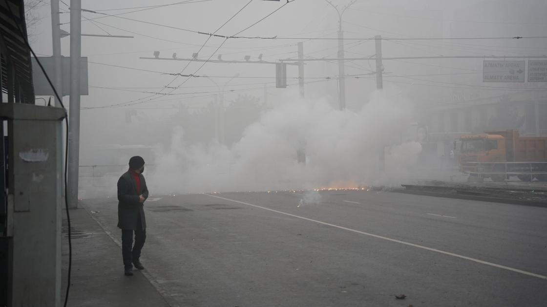 Человек идет по улице, окутанной дымом