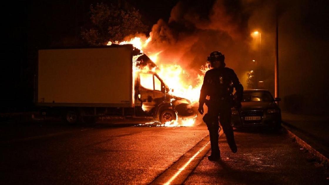 Полицейский на фоне горящей машины