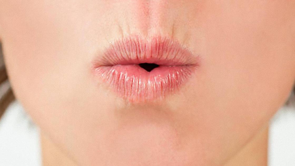 Губы у женщины сложены дудочкой для свиста