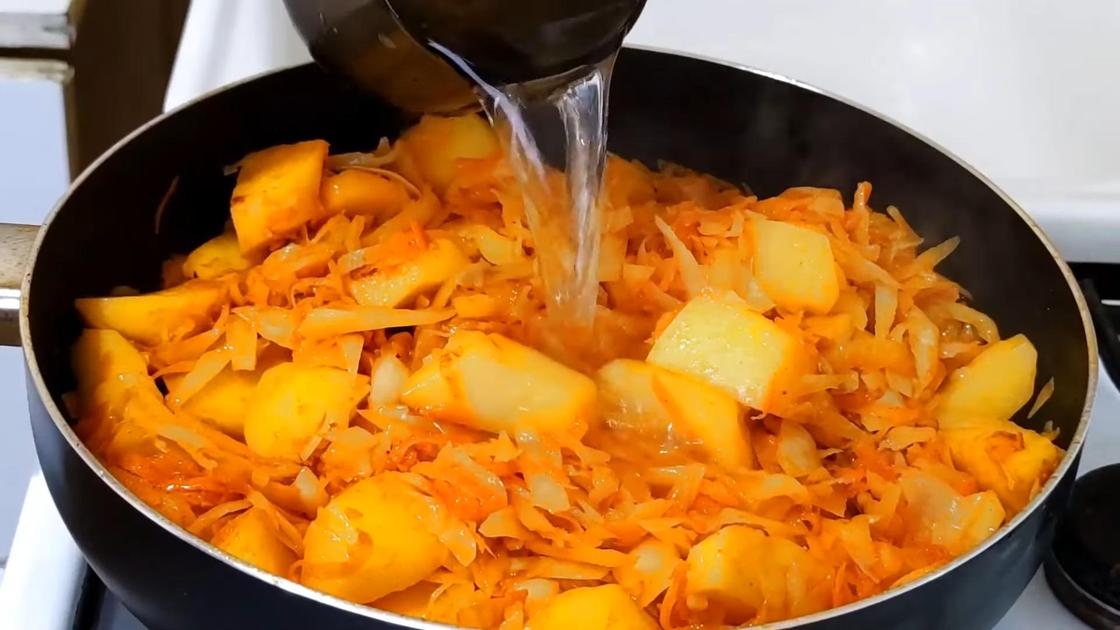 Добавление воды в сковороду с картофелем, капустой, луком и морковью