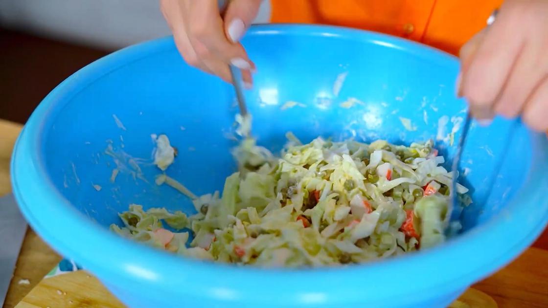 В пластиковой миске смешивают салат с заправкой