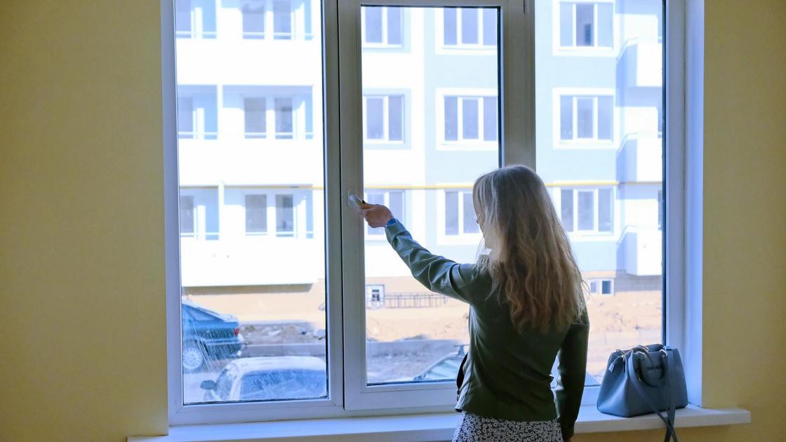 Терезе алдында тұрған әйел