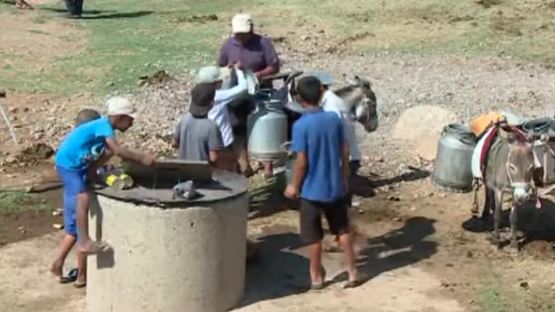 Подростки помогают набирать воду из колодца