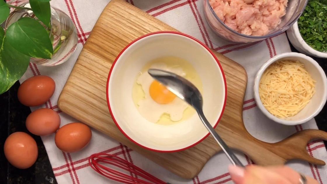 На столе яйца, мясо, сыр. В пиале разбитое яйцо, к которому добавляют молоко