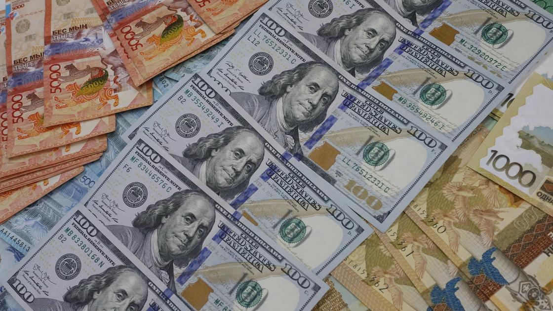 Долларовые банкноты и банкноты тенге лежат рядом