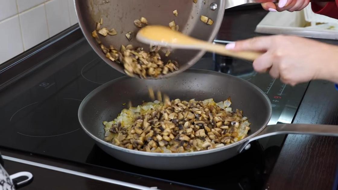Обжаренные дольки шампиньонов пересыпают из сковороды в сковороду с луком