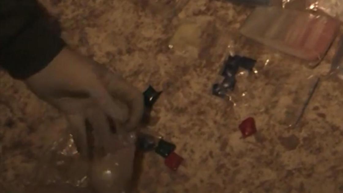 Полицейский высыпает на пол содержимое пакета с синтетическими наркотиками