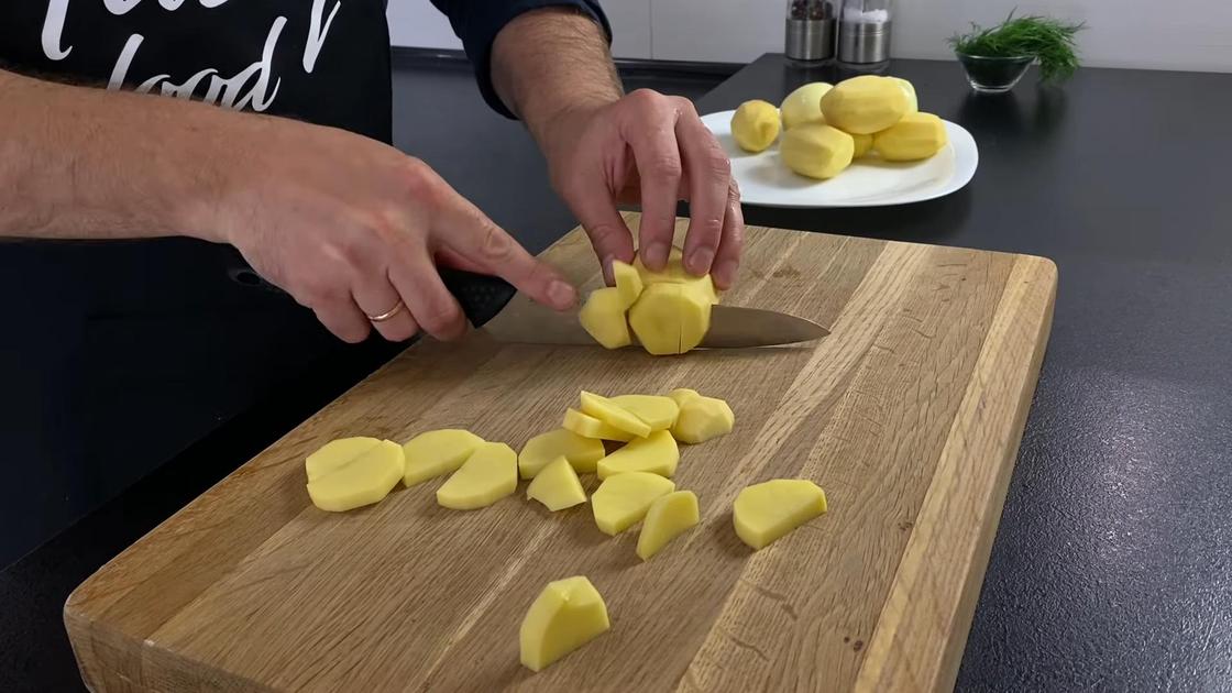 Картофель нарезают дольками на разделочной доске