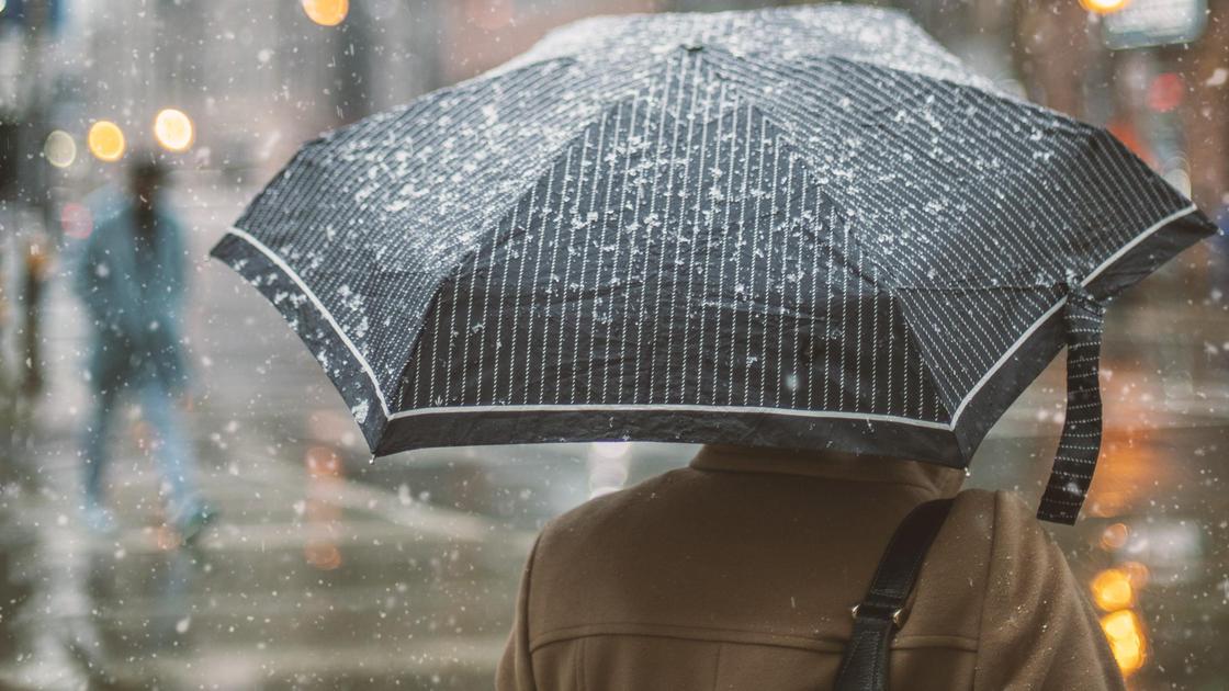 Женщина под зонтом идет по улице