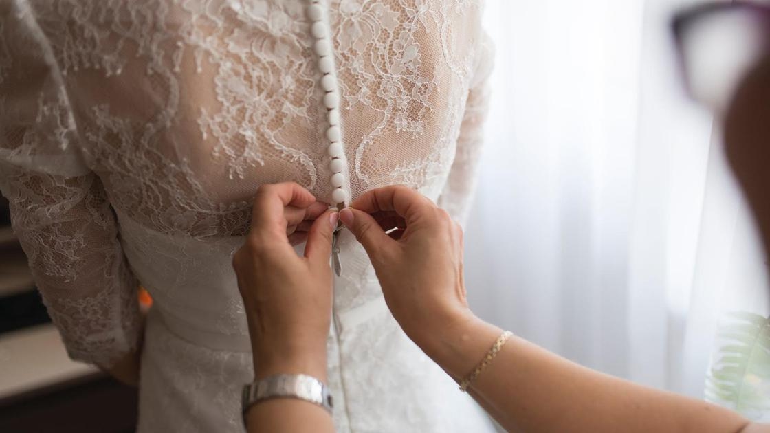 Невесте застегивают подвенечное платье