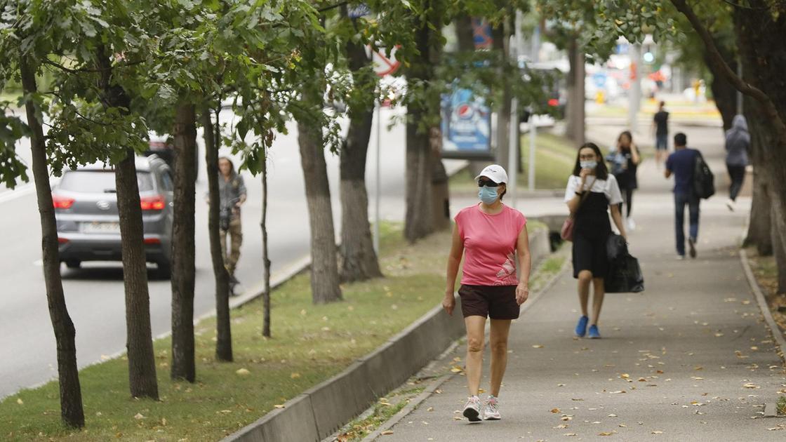 Девушка в спортивной одежде и маске идет по улице