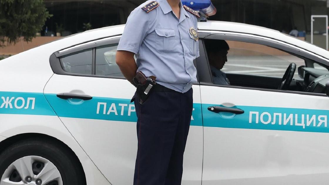 Полицейский в форме стоит возле служебного автомобиля