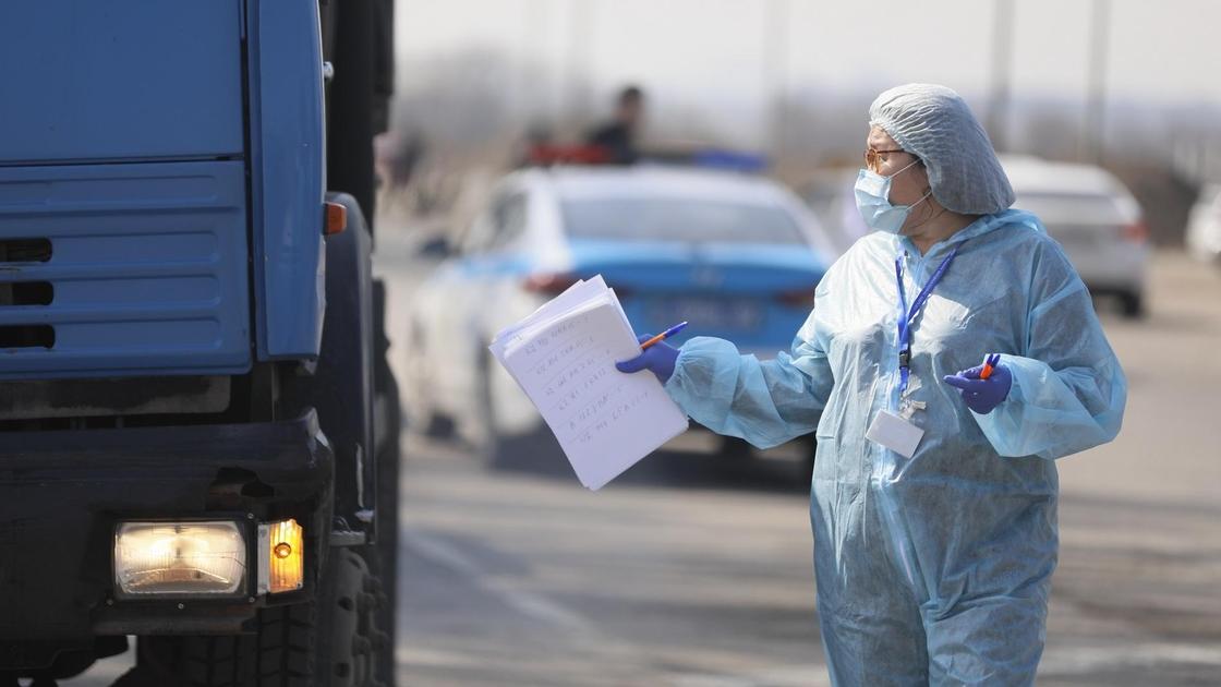 медик в защитном костюме стоит возле грузовика