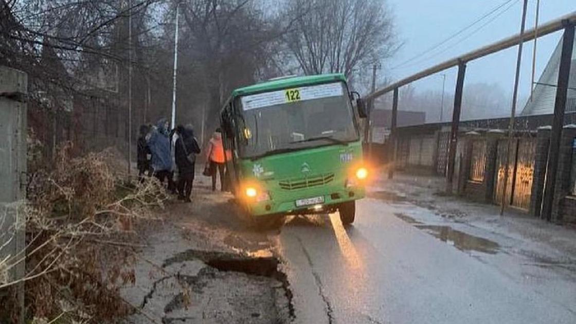 Автобус у обочины дороги, одним колесом провалившийся в яму